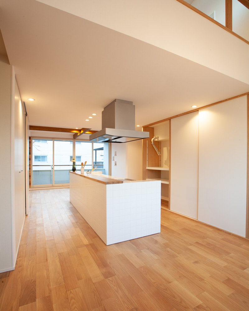 白いタイルのキッチンがアクセントのキッチン。キッチン背面には引き戸で隠せる大型の収納棚を設置。