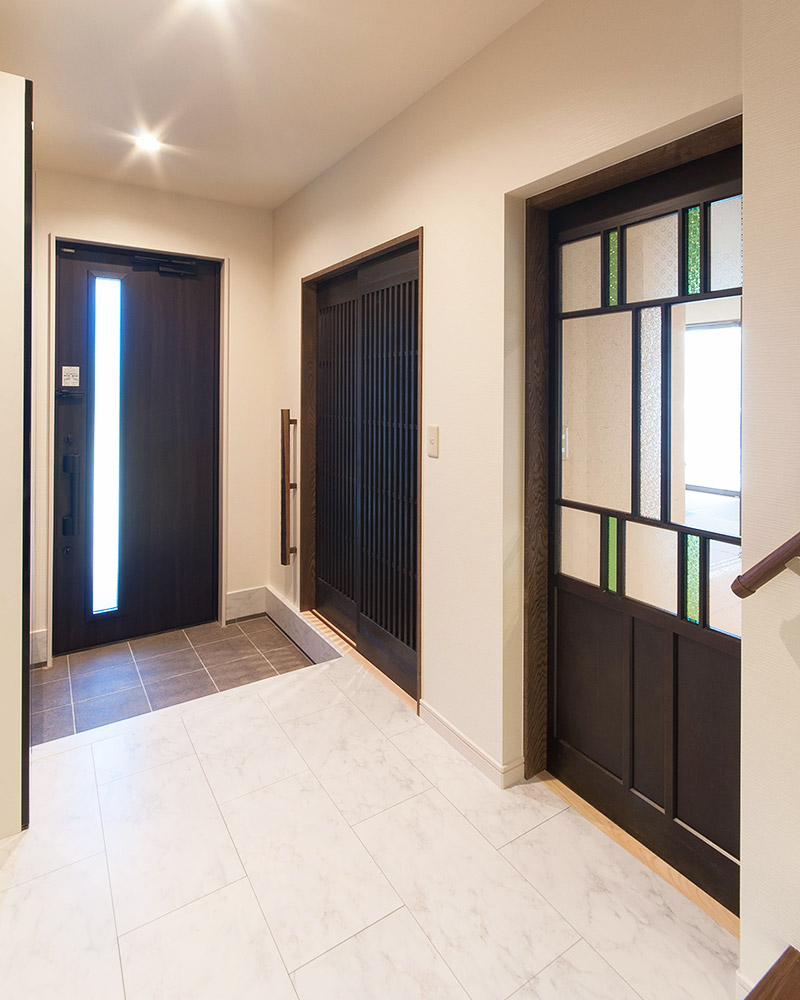 玄関横には収納の格子戸とアンティークなガラスの古建具がある。