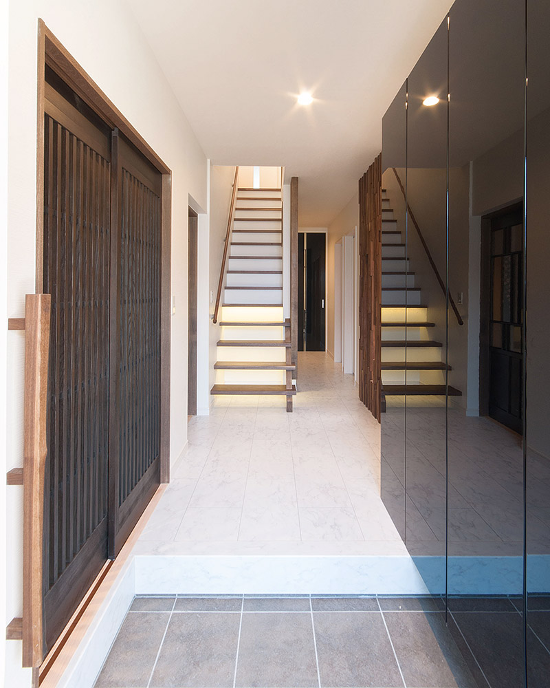 玄関を正面から見ると、左に格子戸、右に黒い鏡面の大きな下駄箱、奥に階段がある。