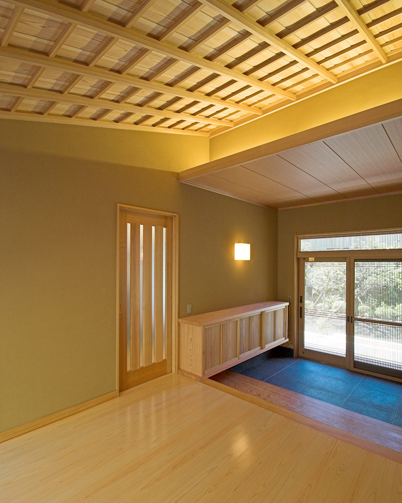 杉の上り竿縁天井の勾配天井を間接照明で照らした玄関。