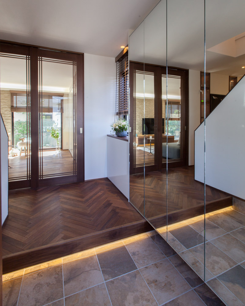 鏡面のシューズクロークとガラスの扉の効果で開放的なホールが広がる。