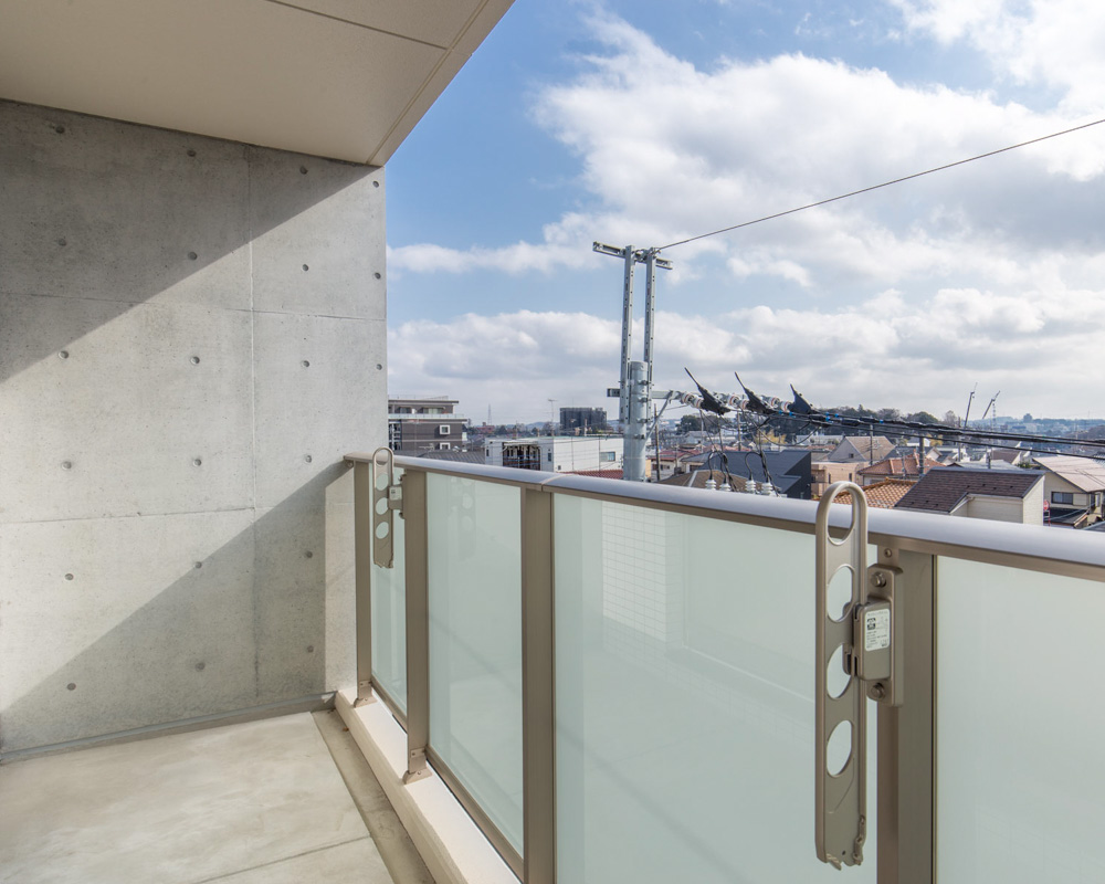 乳白色とブルー系の二色のガラス手すり、アクセントとして暗色系のタイル手すりも採用したベランダ
