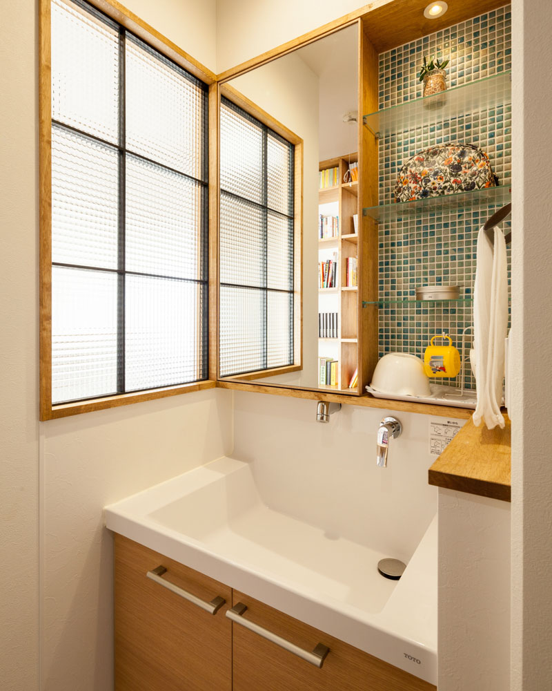 洗面化粧台の横には一工夫。採光にはチェッカーガラスを採用し、プライバシーを守る。