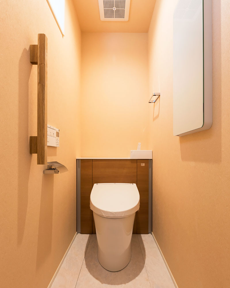 オレンジの壁紙をはったトイレ