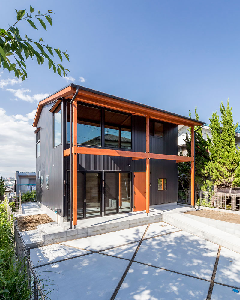 ガルバリウム鋼板にオレンジの木材が映える外観