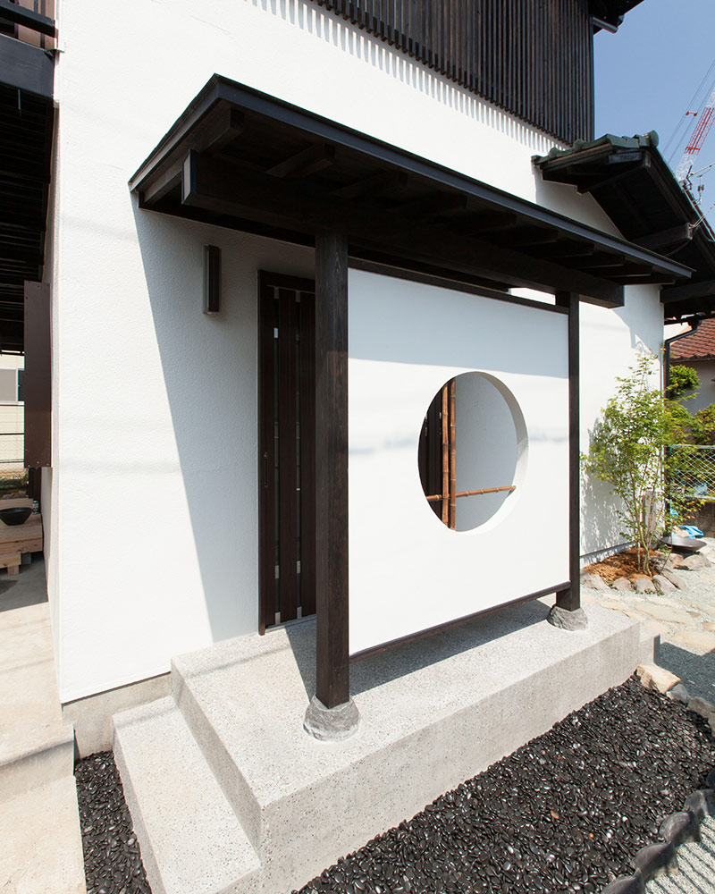 丸窓を設けた目隠し壁がある玄関