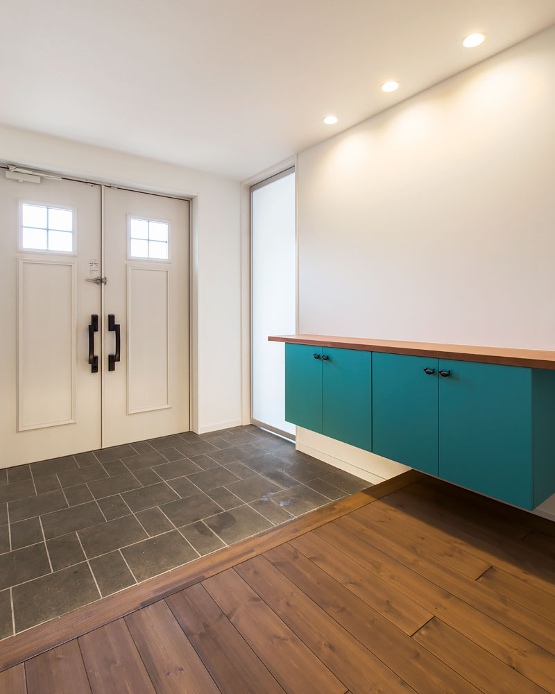 ターコイズブルーの差し色が印象的な下駄箱